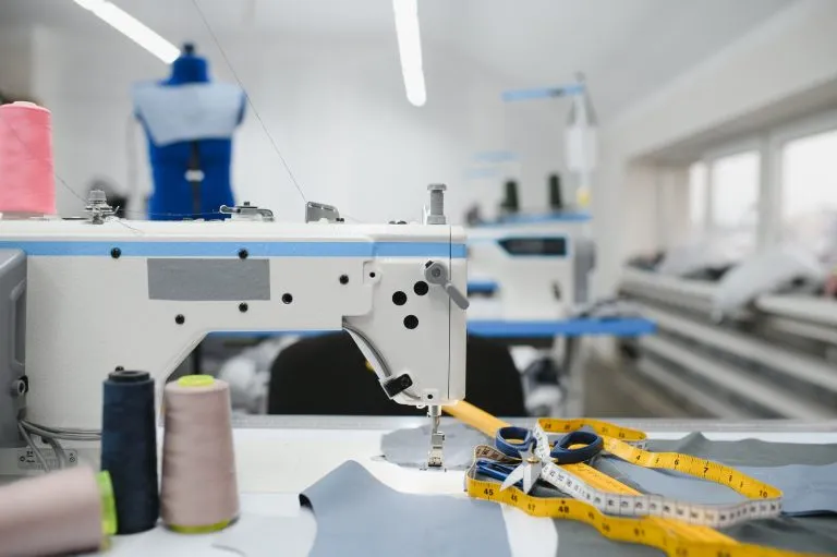 composition-of-sewing-thread-scissors-and-tape-measure-on-a-white-table--768x511